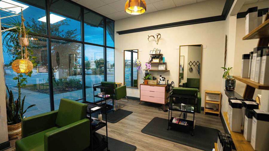 Hair salon suite with green chairs and floor-to-ceiling windows at LUX Salon Suites Prosper